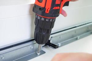 man assembling white table furniture at home using cordless screwdriver photo