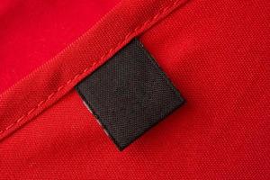 etiqueta de ropa negra en blanco para el cuidado de la ropa sobre fondo de textura de tela roja foto