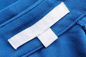 etiqueta de ropa blanca en blanco para el cuidado de la ropa sobre fondo de tela azul foto