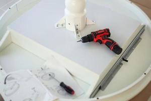 Cordless screwdriver on wood table assembly furniture concept photo