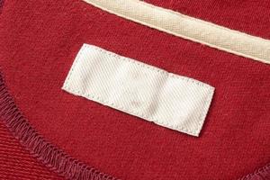 Blank white laundry care clothes label on red fabric texture background photo