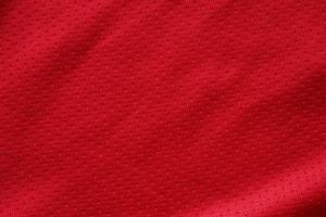 Red sports clothing fabric football shirt jersey texture close up photo