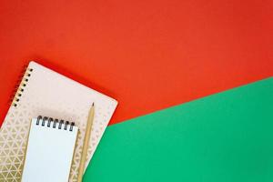 concepto de navidad o vacaciones. mini bloc de notas en espiral blanco y lápiz de madera en el cuaderno rosa dorado. foto
