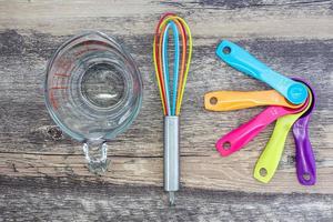 Set of measuring cups, measuring spoons, measuring glass and silicone whisk use in cooking lay on wooden tabletop in top view photo