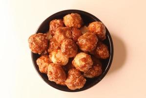 Selective focus of many candied macadamia nuts spinning in a small bowl. photo