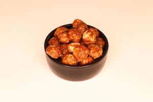 Selective focus of many candied macadamia nuts spinning in a small bowl. photo