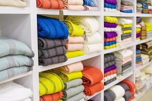 Multicolor towels on shelf in market, sale cotton towels, stack colored cotton photo