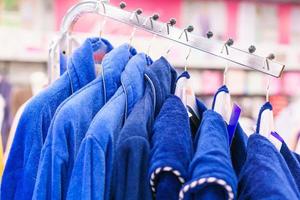 Blue terry bathrobes hang on coat hangers in a store, close-up selective focus. photo