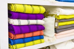 Multicolor towels on shelf in market, sale cotton towels, stack colored cotton photo