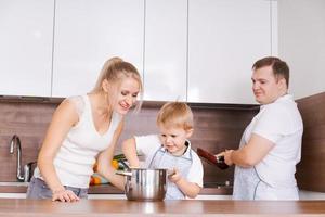 Family mom son, dad are preparing delicious food in kitchen. Mom teaches photo