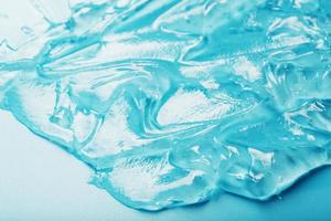 Gel with hyaluronic acid in the form of a smear of glossy texture on a cyan background. photo