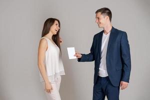 Business partner gives certificate to happy woman on gray background. Caucasian photo