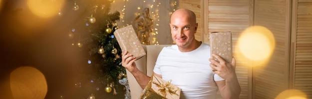 Happy man in chair on the background of Christmas tree with a gift in his hands photo