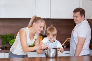 Family mom son, dad are preparing delicious food in kitchen. Mom teaches photo