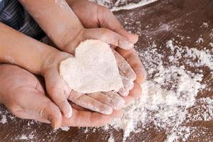 Top view father and child's hand, cut out heart shaped cookies from dough photo