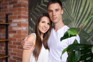Happy couple embracing and looking at camera standing against green background. photo