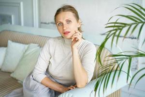 Portrait of a beautiful woman sitting on a sofa in a bright room photo