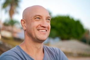 Male portrait happy man with bald head in blue t-shirt smiles with his teeth photo