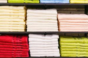 Multicolor towels on shelf in market, sale cotton towels, stack colored cotton photo