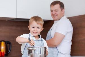 papá e hijo cocinan juntos en la cocina preparando comida, divirtiéndose en casa foto