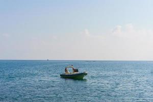 A small open white fisherman stands on the water on a sunny day. photo