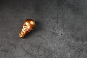 Light bulb from gold on black stone concept of a profitable idea. photo