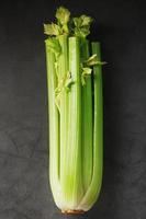 Fresh celery stalks on a black textured background. photo