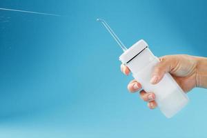 Mouth irrigator in hand on a blue background, for oral care. photo