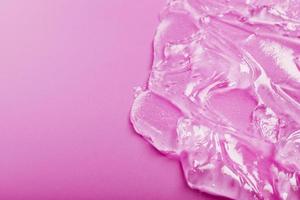 Transparent liquid gel on a pink background with free space. photo