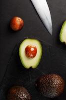 Sliced and whole organic avocado Hass with a knife on a black background. photo