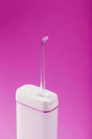 An irrigator for brushing teeth on a pink background. photo