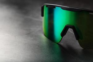 gafas deportivas verdes con lentes de espejo en un fondo oscuro foto