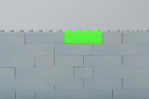 A wall made of children's construction kit parts with bright green bricks. photo