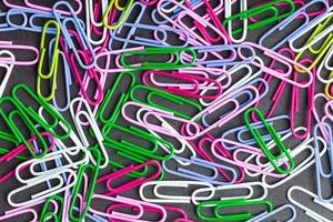 Multicolored paper clips scattered as textured background photo