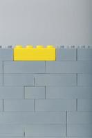 A gray wall made of a toy construction set with the last yellow brick photo