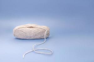 Gray wool of yarn and thread on blue background. Knitting, hobby, winter. Copy space photo