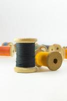 Wooden bobbins for black, yellow,  threads on white isolated background. Handmade, needlework, sewing items. Copy space photo