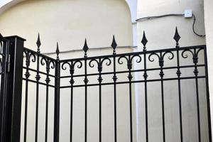A classic yellow house and a beautiful iron fence with a gate. photo