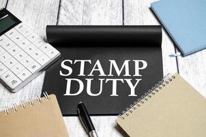 The word stamp duty written on notepad on wooden background photo