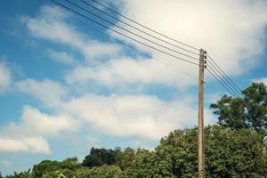 Modern electricity pole with lantern and power line cables. Blue sky and cloud as background. Concept of modern engineering knowledge for power transmission, connection, communication, and lighting photo