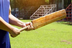 A clicker player holds a bat in his hand as he waits to receive a clicket from the bowler of the other team. Soft and selective focus. photo