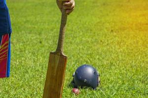 A clicket player holds a bat in his hand while the game is on the sidelines. Soft and selective focus. photo