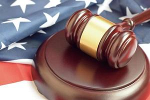 Justice mallet on United States flag in a courtroom during a judicial trial. Law concept and empty copyspace. Judge hammer photo