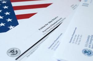 I-130 Petition for alien relative blank form lies on United States flag with envelope from Department of Homeland Security photo