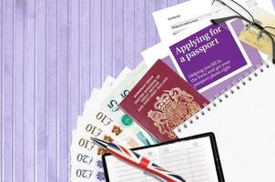 la guía violeta inglesa que solicita un pasaporte se encuentra en la mesa con artículos de oficina. Papeleo del pasaporte del Reino Unido foto