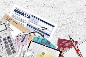 English Tax form P60 End of year certificate by HM revenue and customs lies on table with office items. HMRC paperwork and tax paying process in United Kingdom photo