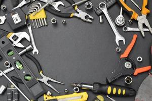 Handyman tool kit on black wooden table with copy space. Many wrenches and screwdrivers, pilers and other tools for any types of repair or construction works. Repairman tools photo