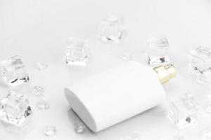 Female perfume mat white bottle, objective photograph of perfume bottle in ice cubes and water on white table. View from above. Mockup product photo, concept of freshness photo