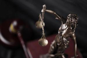 The Statue of Justice - lady justice or justitia the Roman goddess of Justice. Statue on brown book with judge gavel. Concept of judicial trial, courtroom process and lawyers work photo