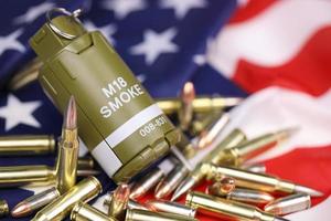 M18 smoke grenade and many yellow bullets and cartridges on United States flag. Concept of gun trafficking on USA territory or spec ops photo